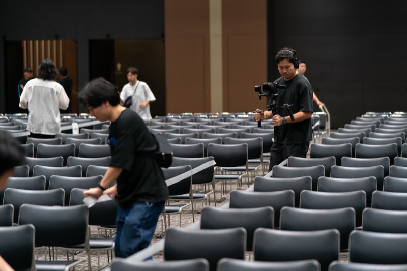 開場前の会場でカメラマンが撮影機材を準備している様子